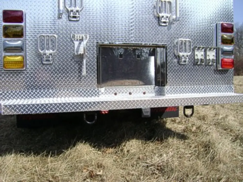 Exterior view of small fire truck showing cab, body compartments, and wheel/tire area.