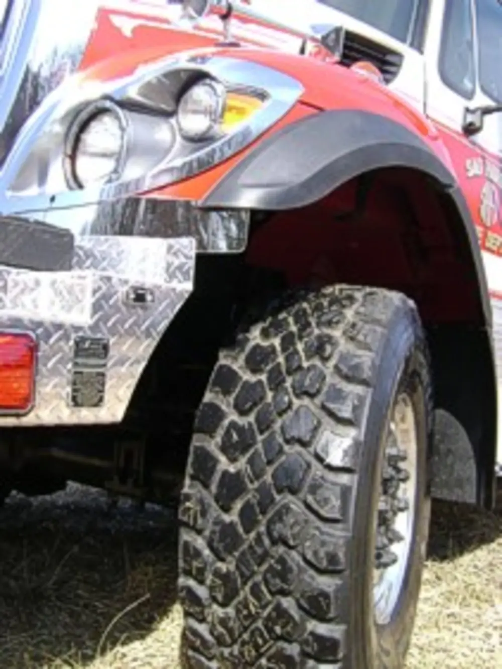 Exterior view of small fire truck showing cab, body compartments, and wheel/tire area.