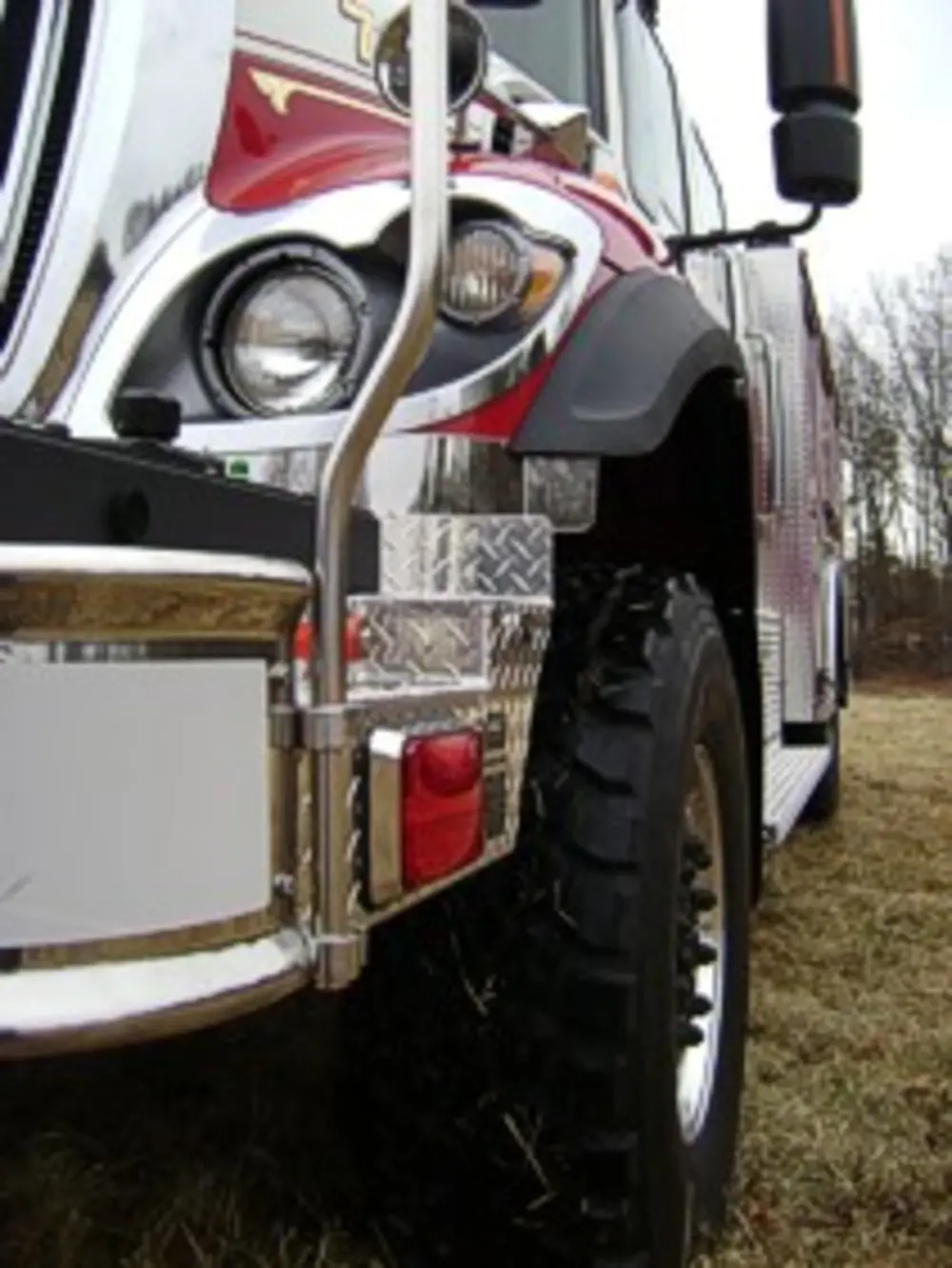 Exterior view of small fire truck showing cab, body compartments, and wheel/tire area.