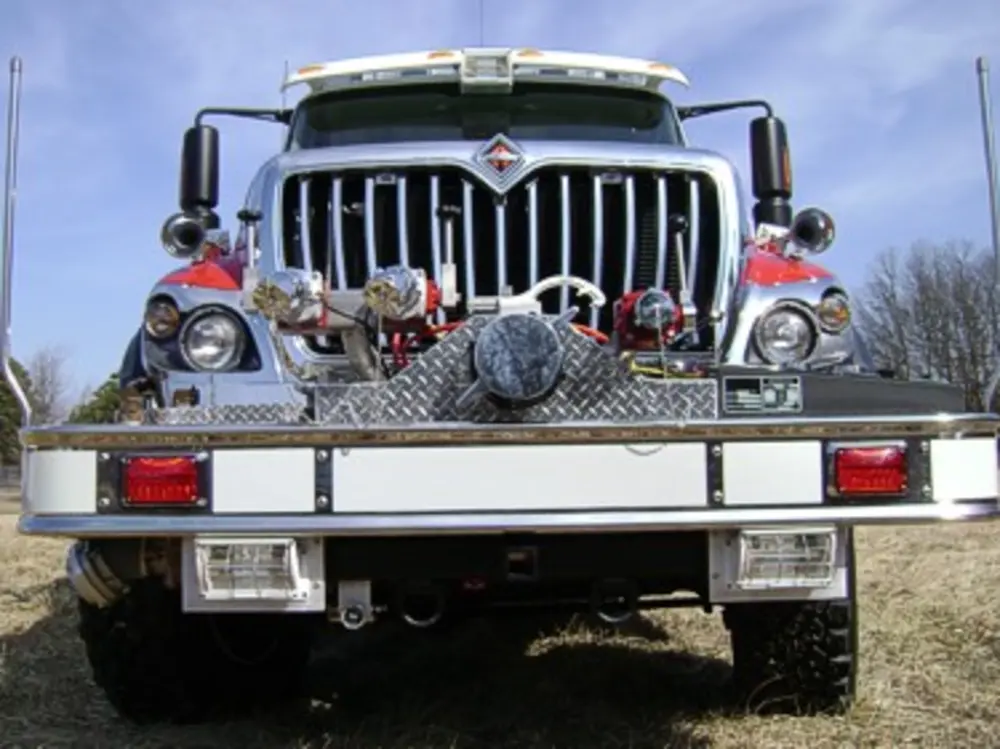 Exterior view of small fire truck showing cab, body compartments, and wheel/tire area.