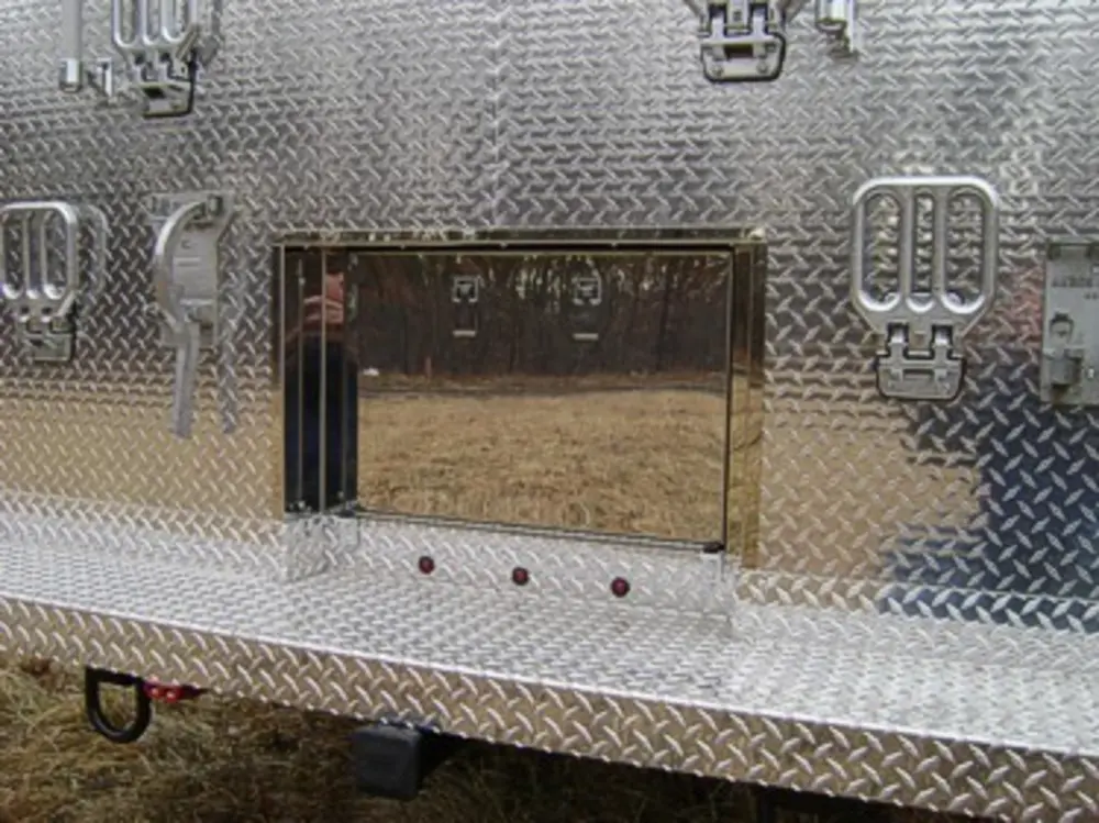 Exterior view of small fire truck showing cab, body compartments, and wheel/tire area.