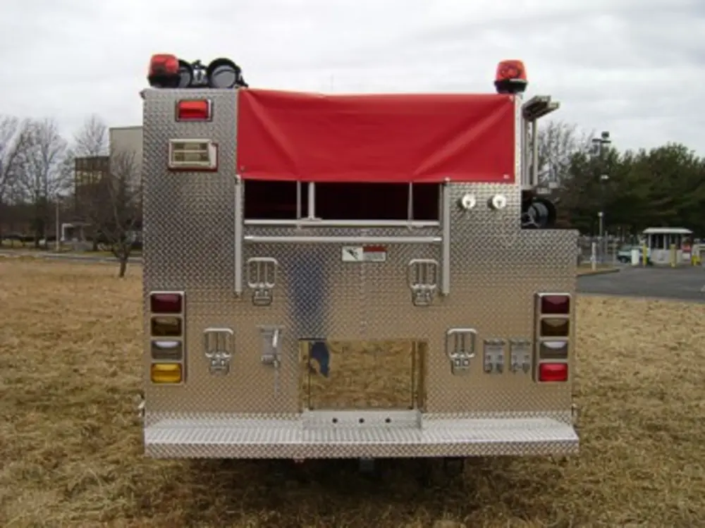 Exterior view of small fire truck showing cab, body compartments, and wheel/tire area.