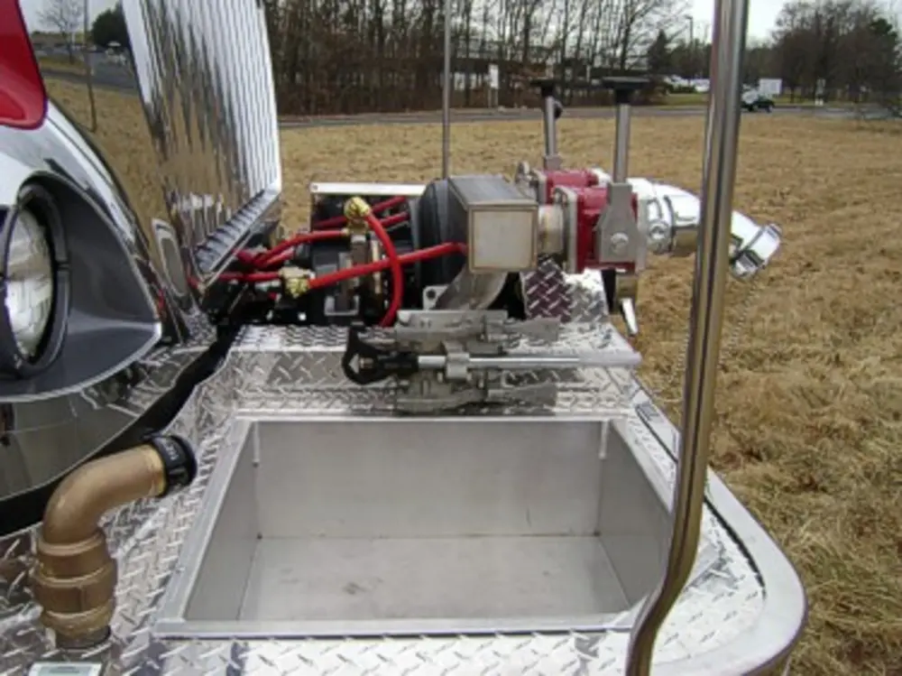 Exterior view of small fire truck showing cab, body compartments, and wheel/tire area.