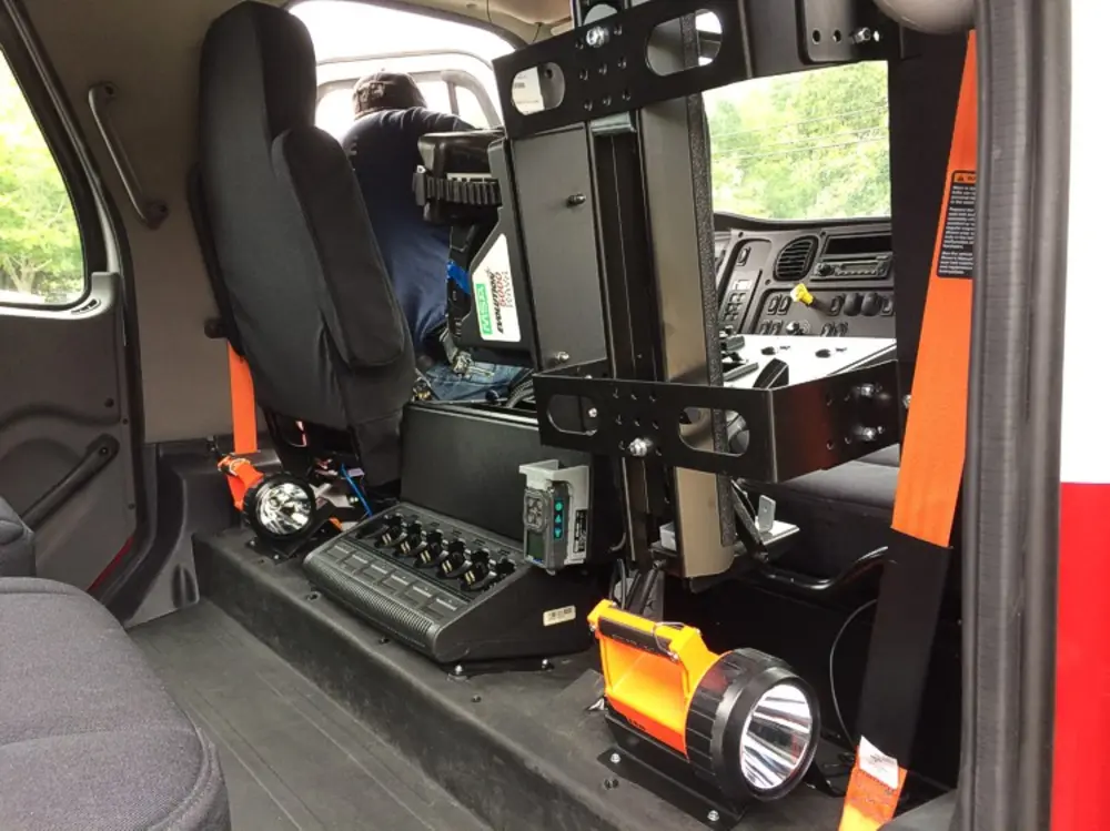 Exterior view of small fire truck showing cab, body compartments, and wheel/tire area.