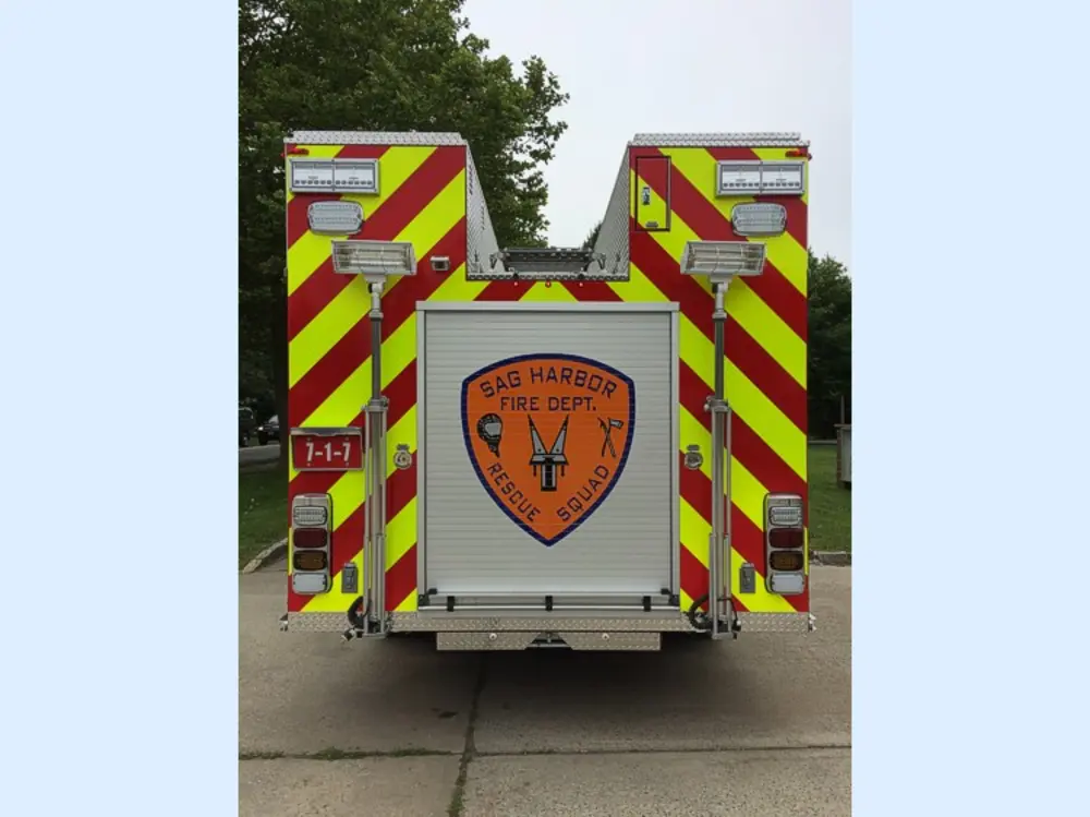 Exterior view of small fire truck showing cab, body compartments, and wheel/tire area.