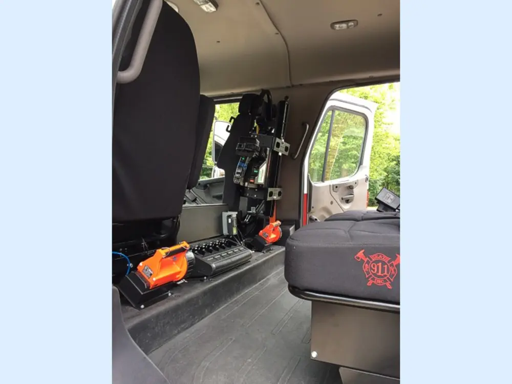 Exterior view of small fire truck showing cab, body compartments, and wheel/tire area.
