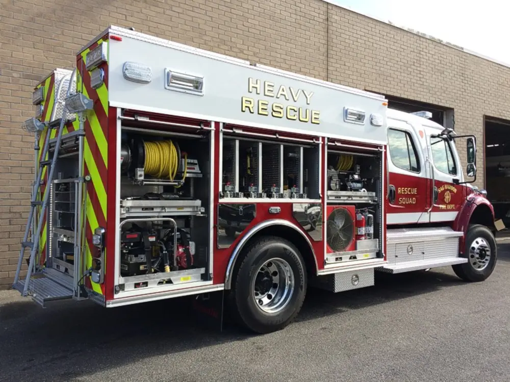 Exterior view of small fire truck showing cab, body compartments, and wheel/tire area.