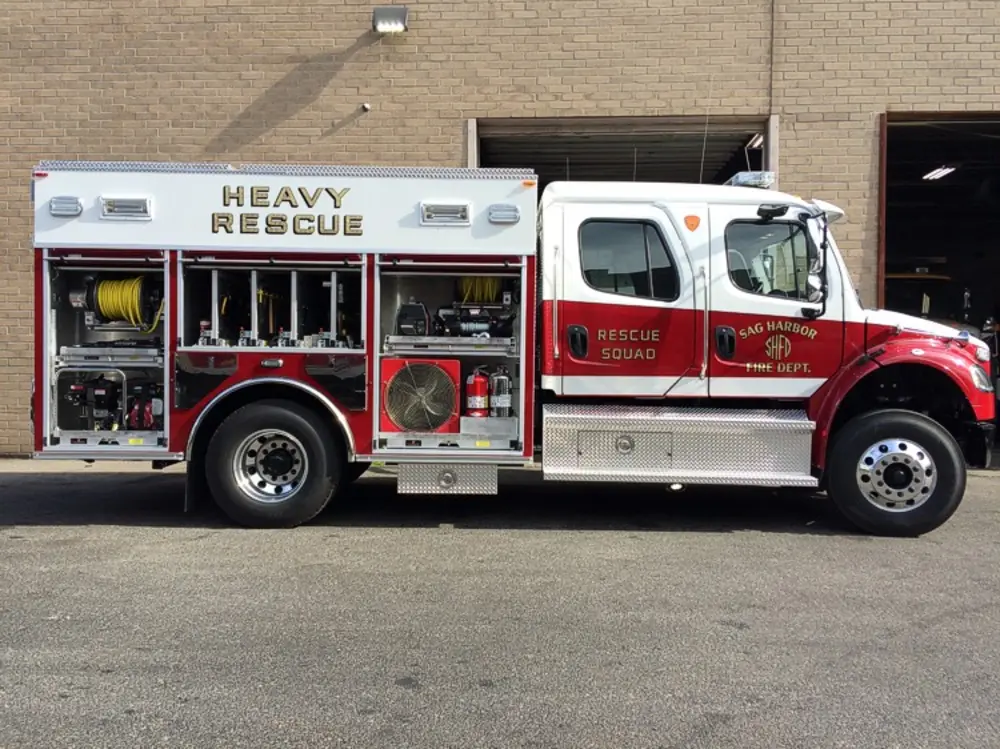 Exterior view of small fire truck showing cab, body compartments, and wheel/tire area.