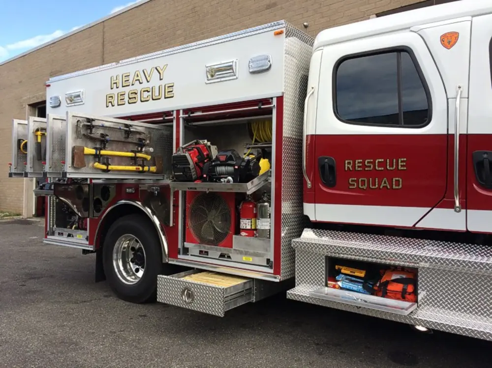 Exterior view of small fire truck showing cab, body compartments, and wheel/tire area.