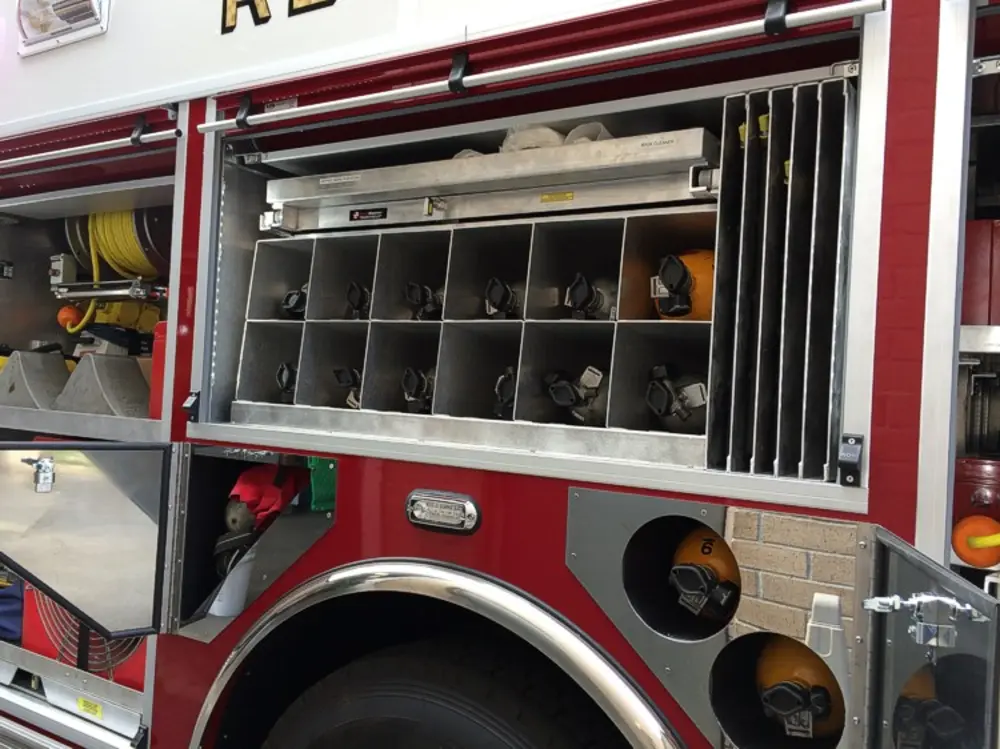 Exterior view of small fire truck showing cab, body compartments, and wheel/tire area.
