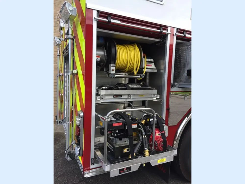 Exterior view of small fire truck showing cab, body compartments, and wheel/tire area.