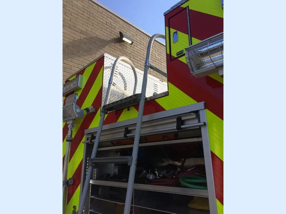 Exterior view of small fire truck showing cab, body compartments, and wheel/tire area.