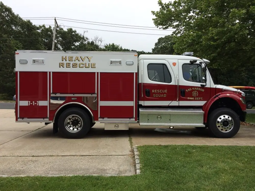 Exterior view of small fire truck showing cab, body compartments, and wheel/tire area.