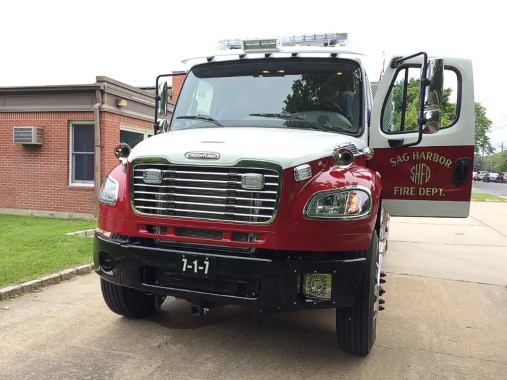 Exterior view of small fire truck showing cab, body compartments, and wheel/tire area.