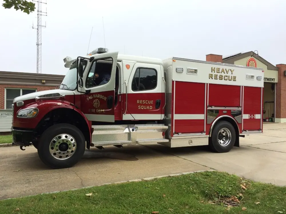 Exterior view of small fire truck showing cab, body compartments, and wheel/tire area.