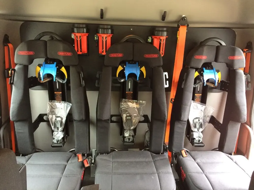 Exterior view of small fire truck showing cab, body compartments, and wheel/tire area.