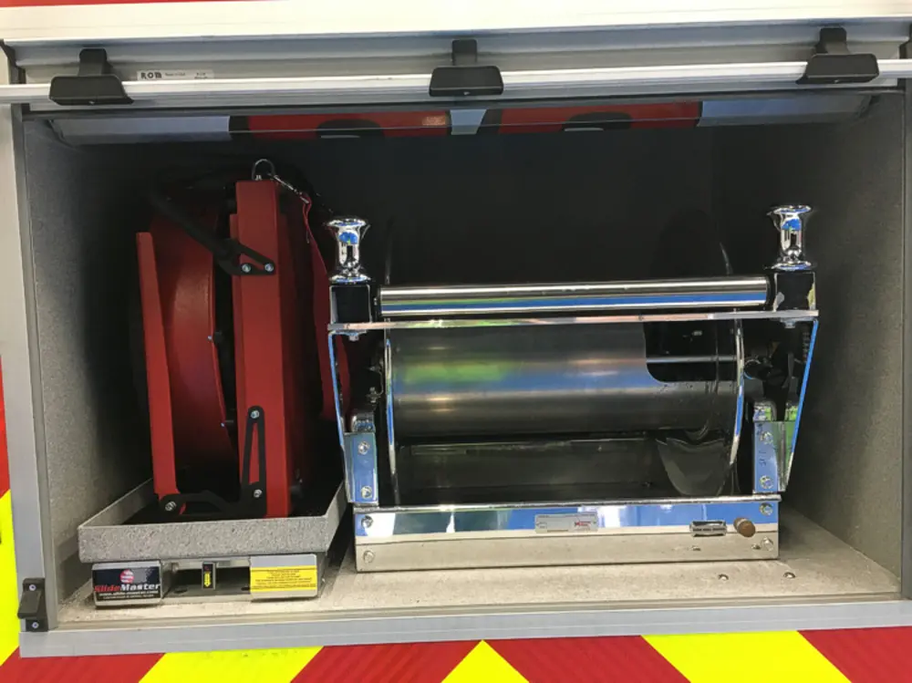 Exterior view of small fire truck showing cab, body compartments, and wheel/tire area.