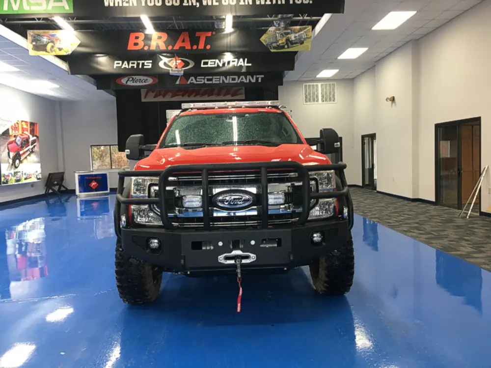 Exterior view of small fire truck showing cab, body compartments, and wheel/tire area.