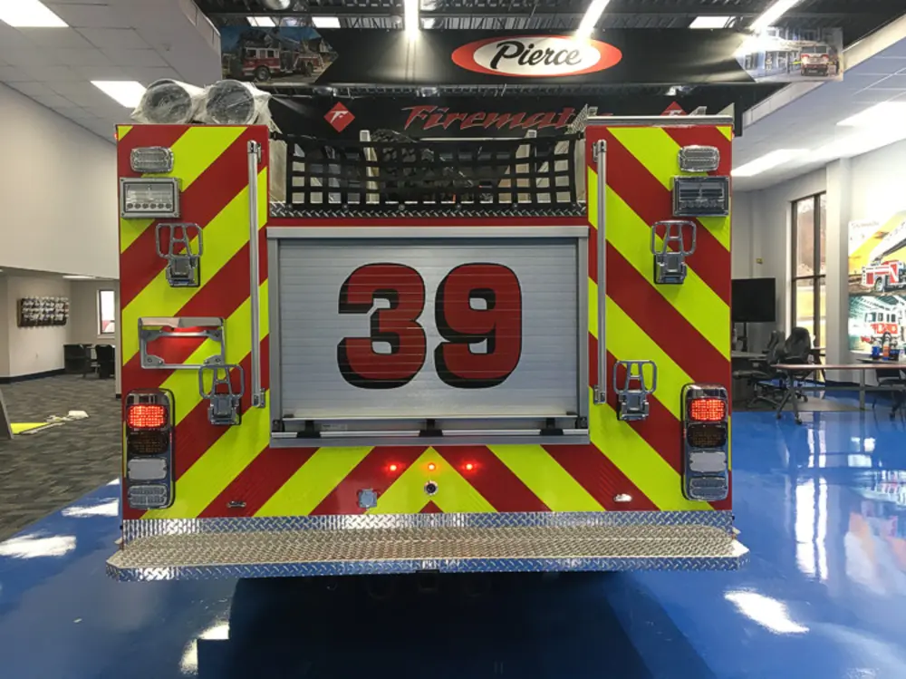 Exterior view of small fire truck showing cab, body compartments, and wheel/tire area.