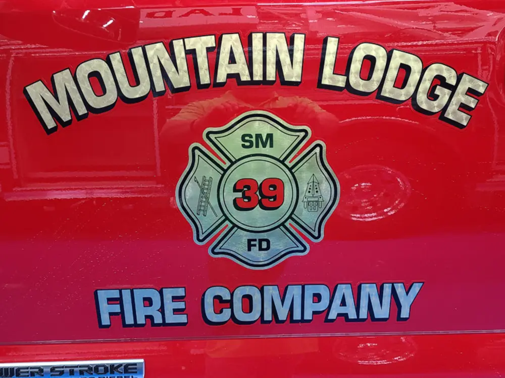 Exterior view of small fire truck showing cab, body compartments, and wheel/tire area.