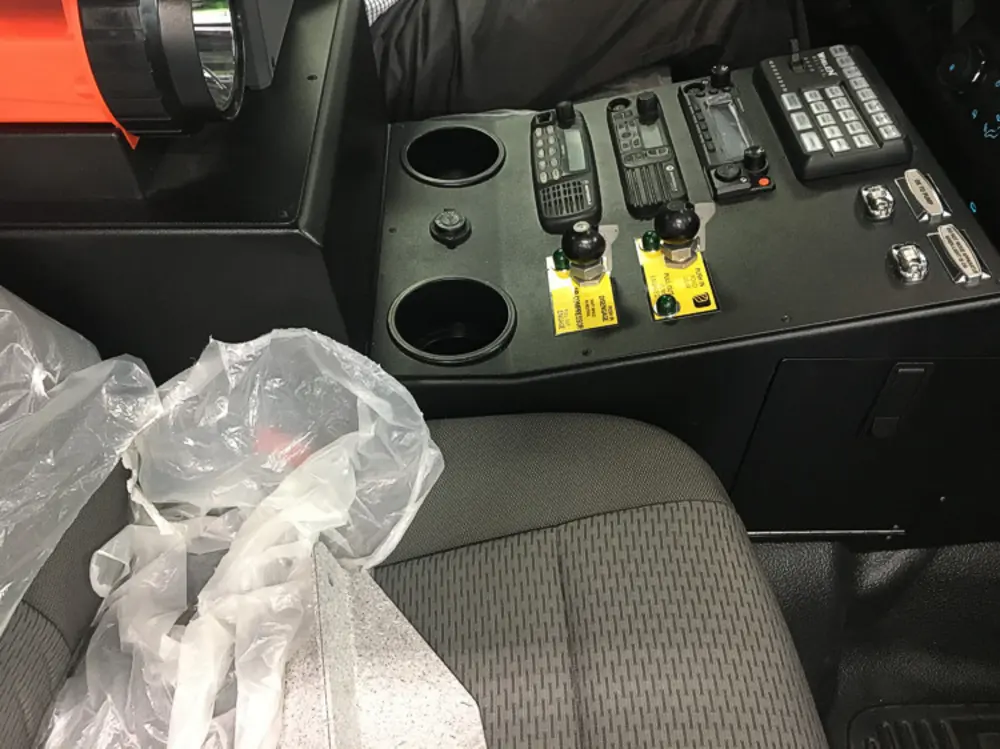 Exterior view of small fire truck showing cab, body compartments, and wheel/tire area.