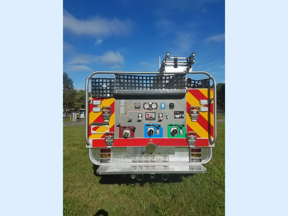 Exterior view of small fire truck showing cab, body compartments, and wheel/tire area.