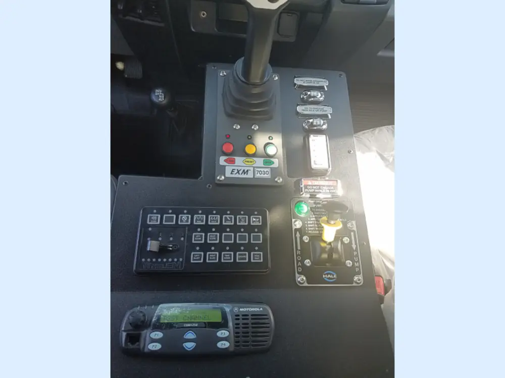 Exterior view of small fire truck showing cab, body compartments, and wheel/tire area.