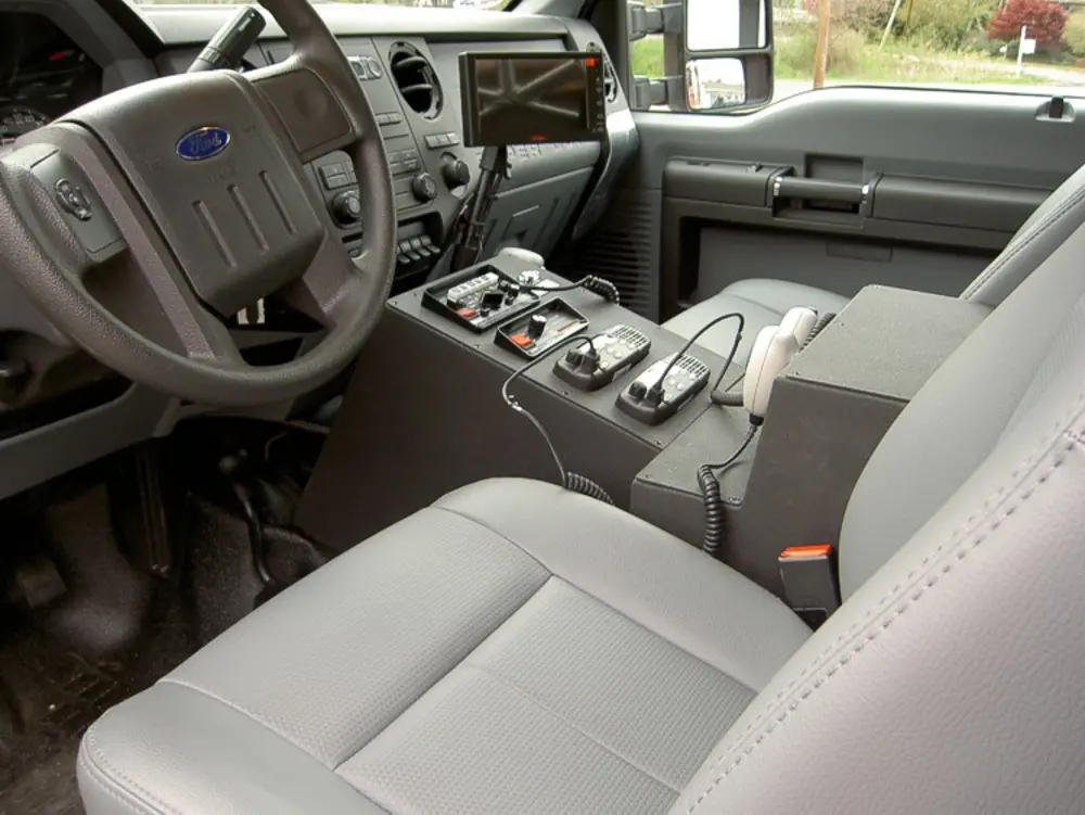 Exterior view of small fire truck showing cab, body compartments, and wheel/tire area.