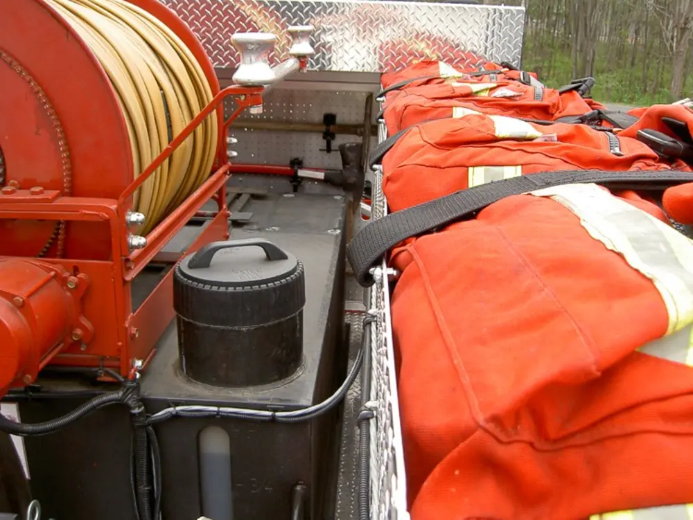 Exterior view of small fire truck showing cab, body compartments, and wheel/tire area.
