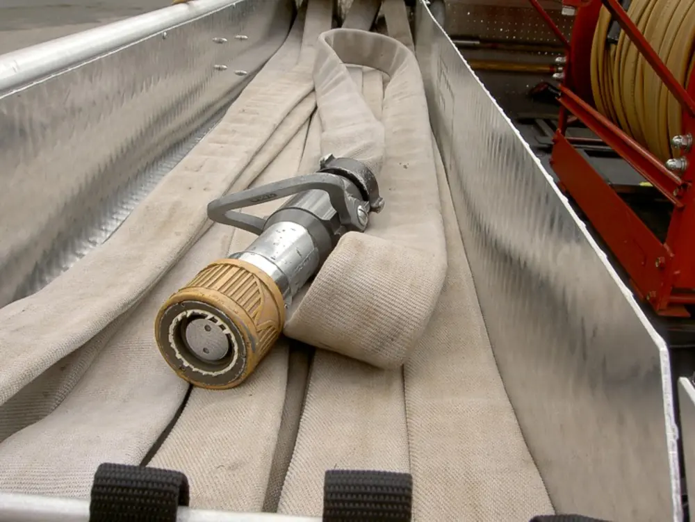 Exterior view of small fire truck showing cab, body compartments, and wheel/tire area.