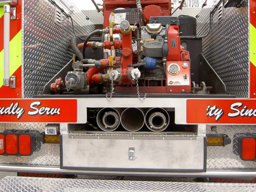 Exterior view of small fire truck showing cab, body compartments, and wheel/tire area.