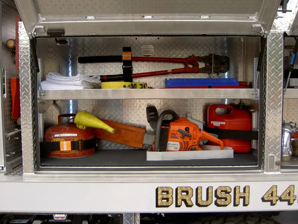 Exterior view of small fire truck showing cab, body compartments, and wheel/tire area.