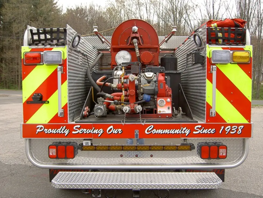 Exterior view of small fire truck showing cab, body compartments, and wheel/tire area.