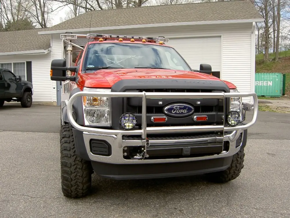 Exterior view of small fire truck showing cab, body compartments, and wheel/tire area.