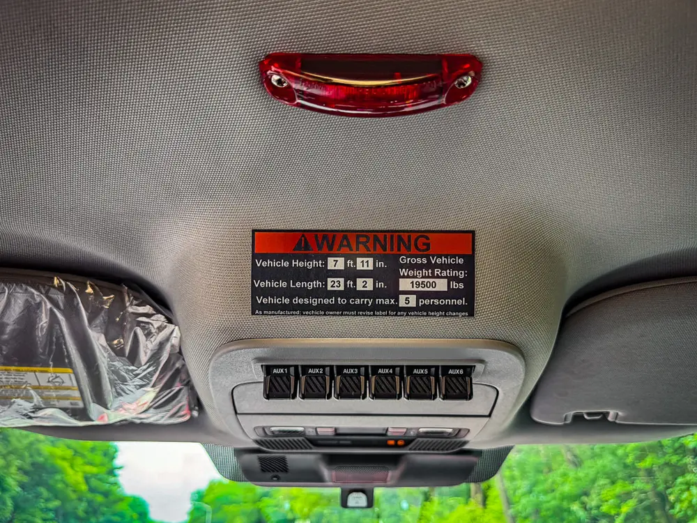 Headliner warning label and overhead light close-up inside cab.
