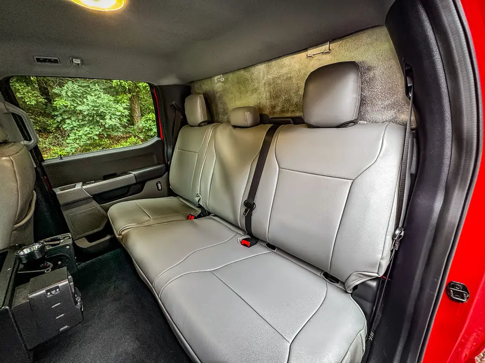 Rear bench seat close-up with equipment mounted on floor beside seat.