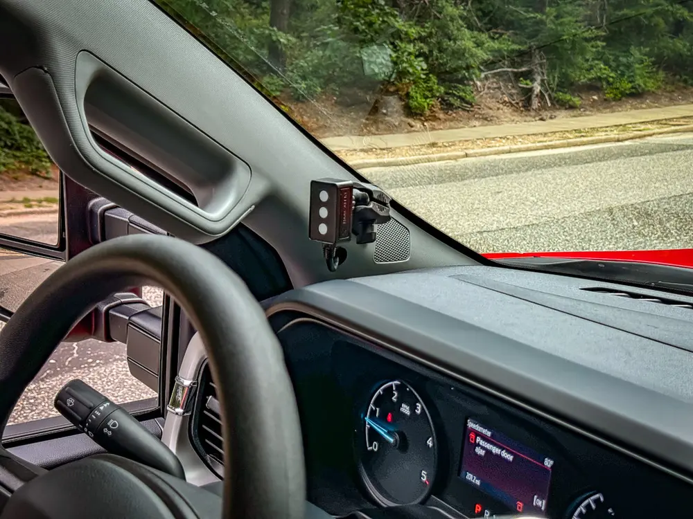 Dashboard corner view with steering wheel and side-mounted control device.