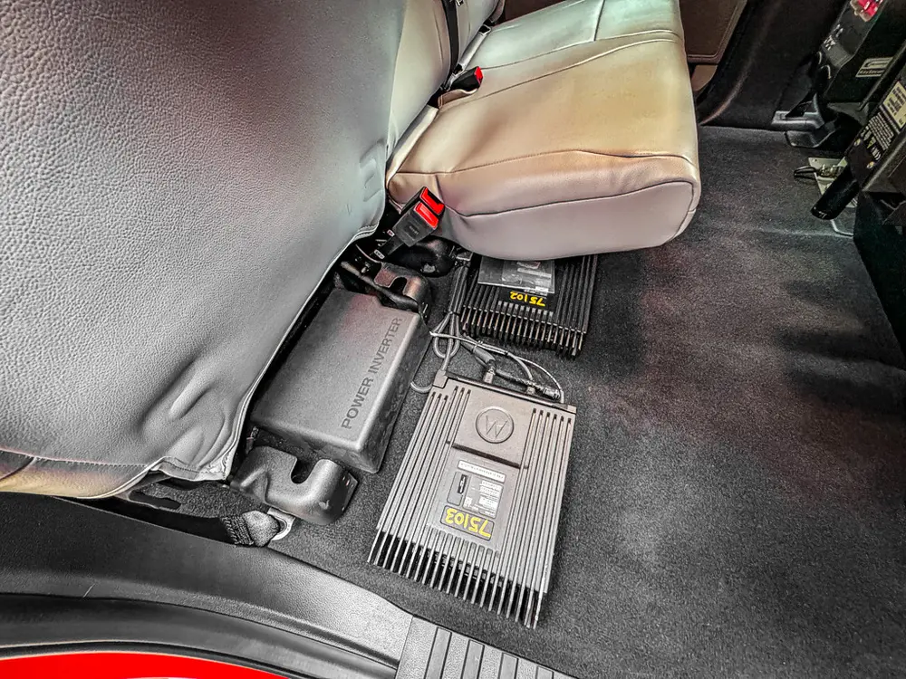 Rear footwell close-up with mounted equipment module behind seat.