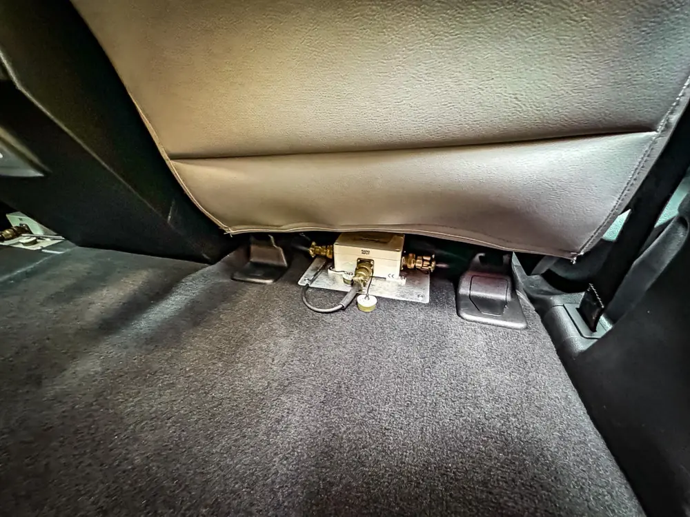 Rear footwell close-up with wiring and connectors beneath seat.