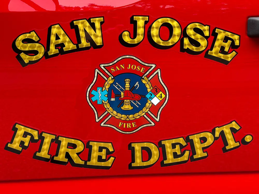 Tight close-up of San Jose Fire Dept emblem and lettering on red panel.