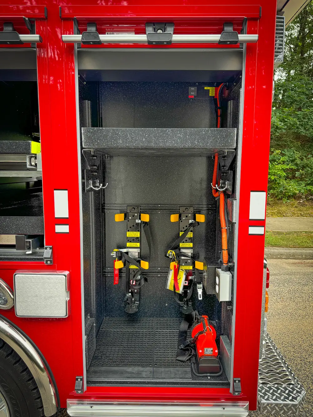 Narrow vertical side compartment with mounted yellow-handled tools.