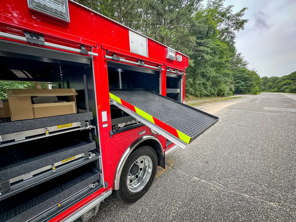 Open side compartment with extended tray and boxed equipment near cab.