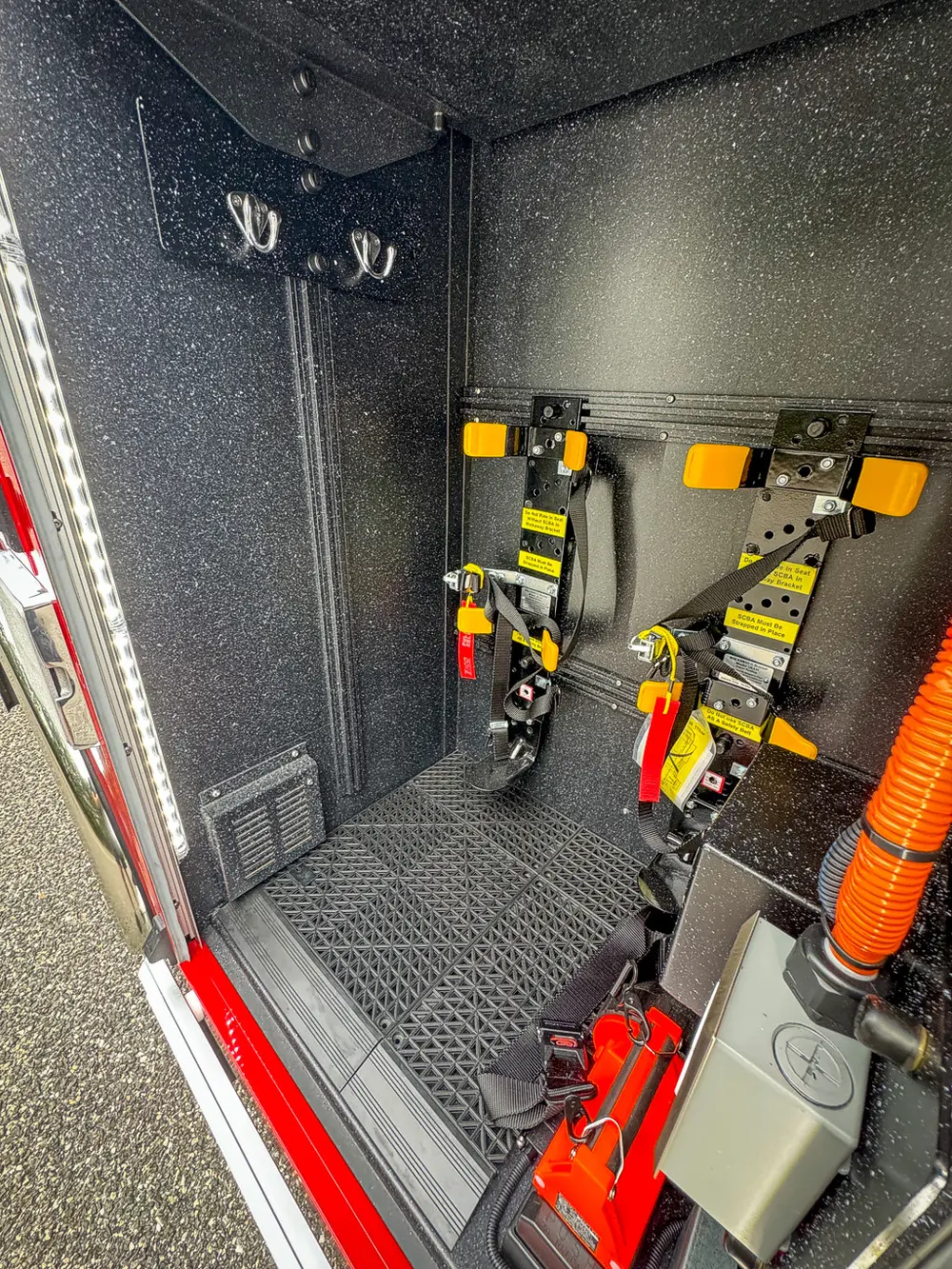 Narrow vertical storage bay with mounted straps and power connections.