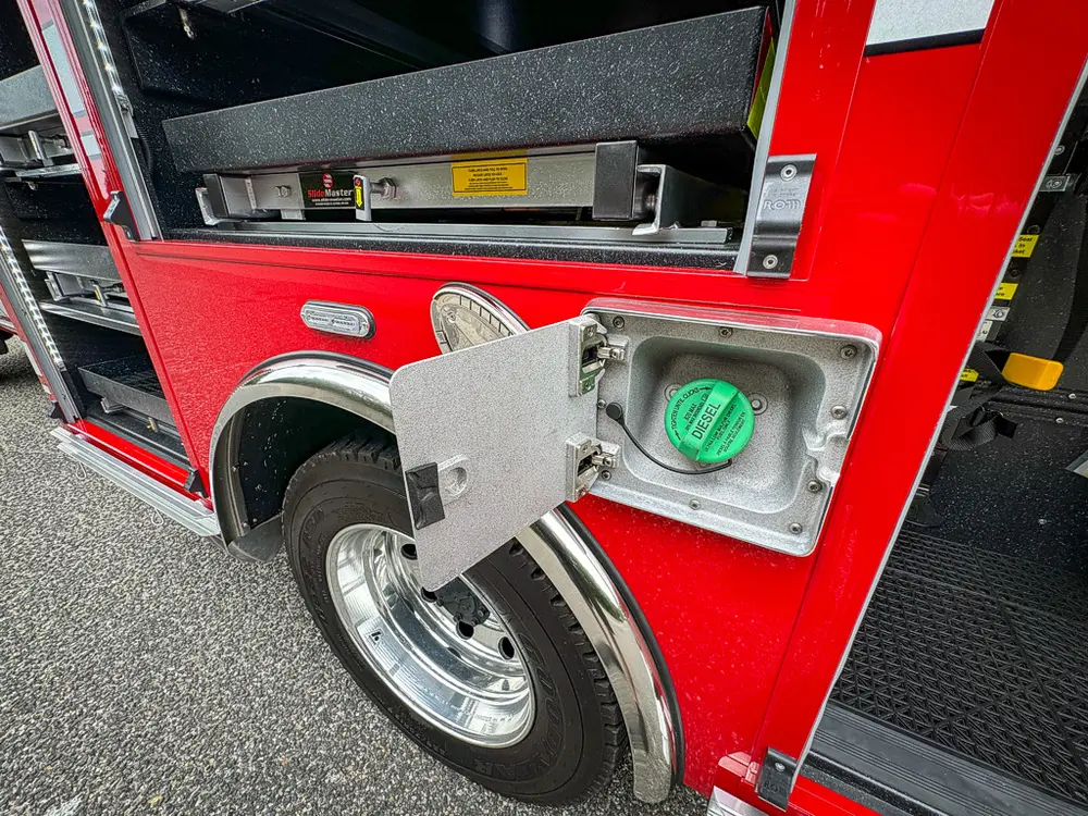 Open side intake-port door showing green fitting near wheel arch.