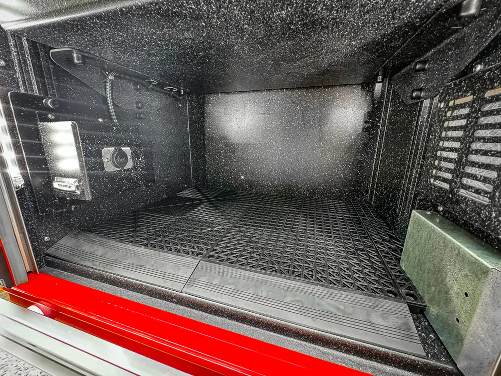 Deep equipment bay close-up with interior lighting and dark storage floor.
