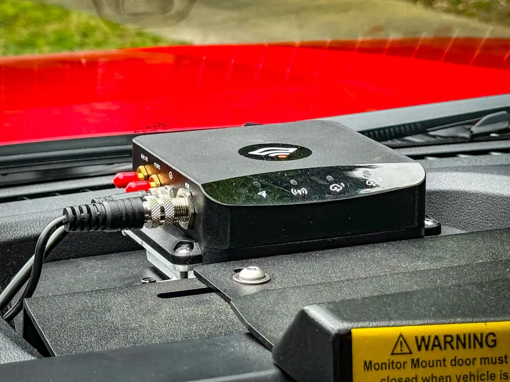 Dashboard-mounted electronics box close-up with cables connected.