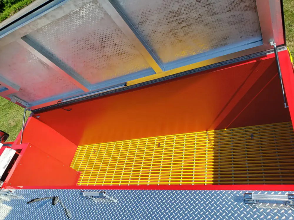 Exterior view of small fire truck showing cab, body compartments, and wheel/tire area.