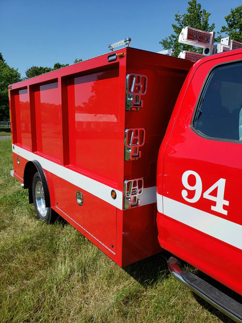 Exterior view of small fire truck showing cab, body compartments, and wheel/tire area.