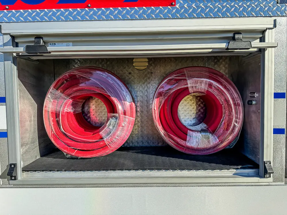 Compartment close-up with two red coiled hoses side by side.