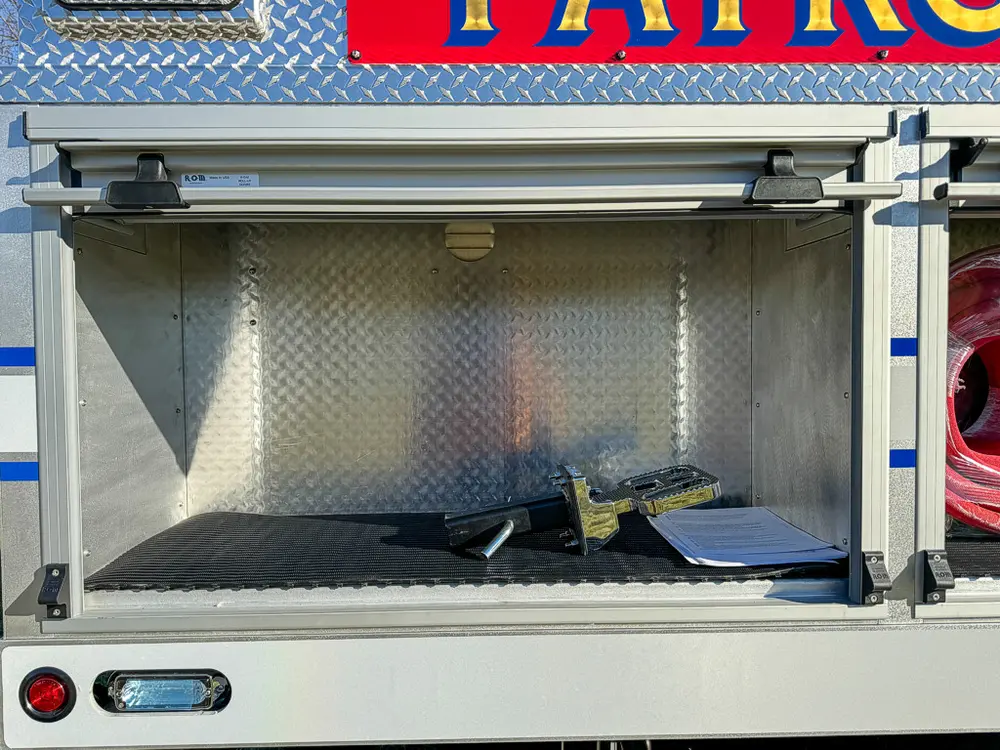 Open side compartment with shelf and small loose items on floor.